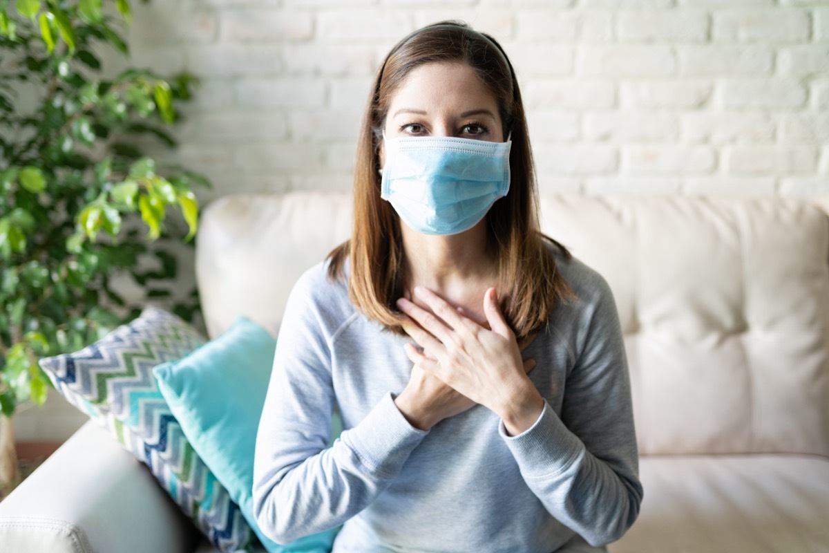 Portrait of a beautiful woman with surgical mask and hands on her heart sending love to family and friends during covid19 coronavirus pandemic