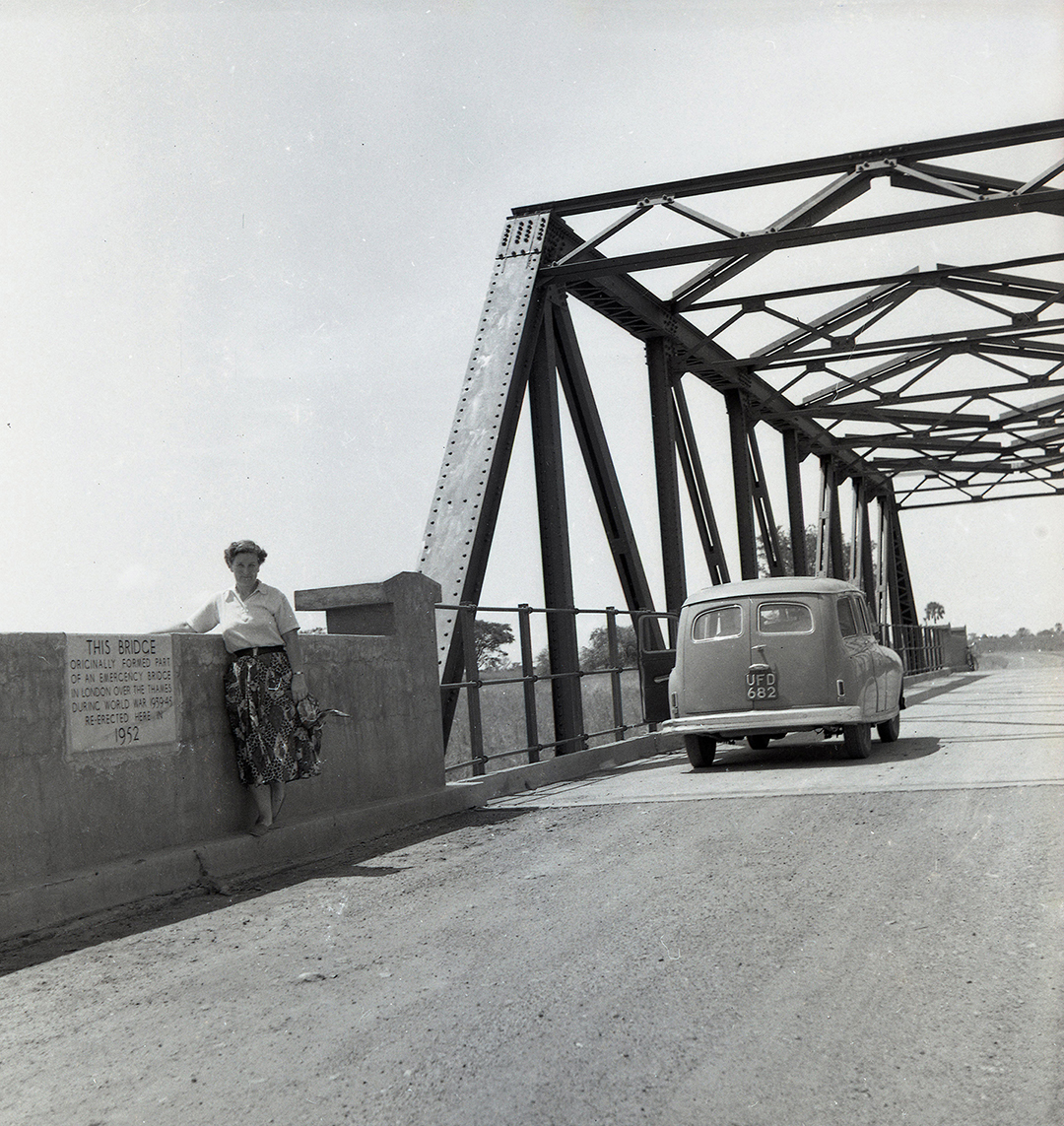 a woman poses in front of a bridge