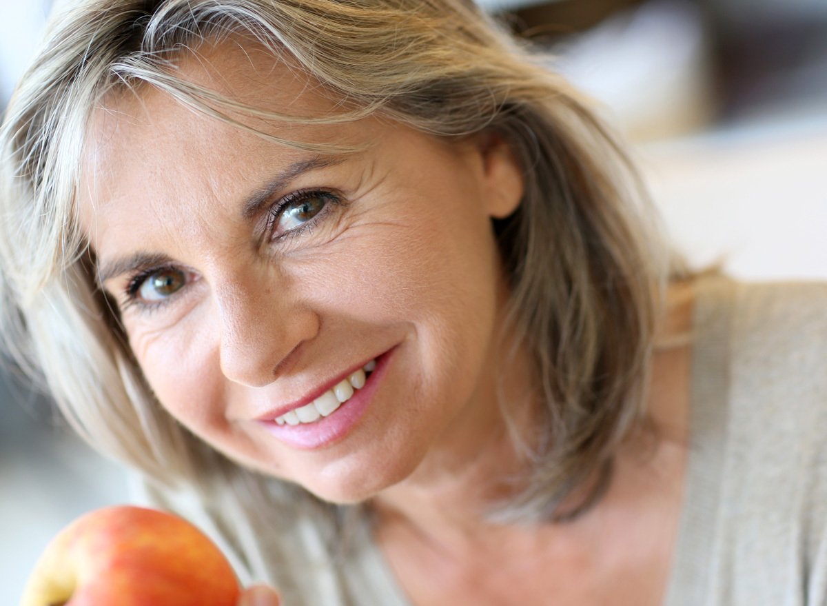 Mature older woman eating an apple with great skin