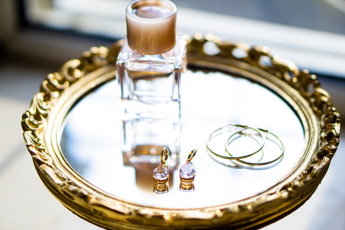 earrings and perfume bottle on gold mirrored tray