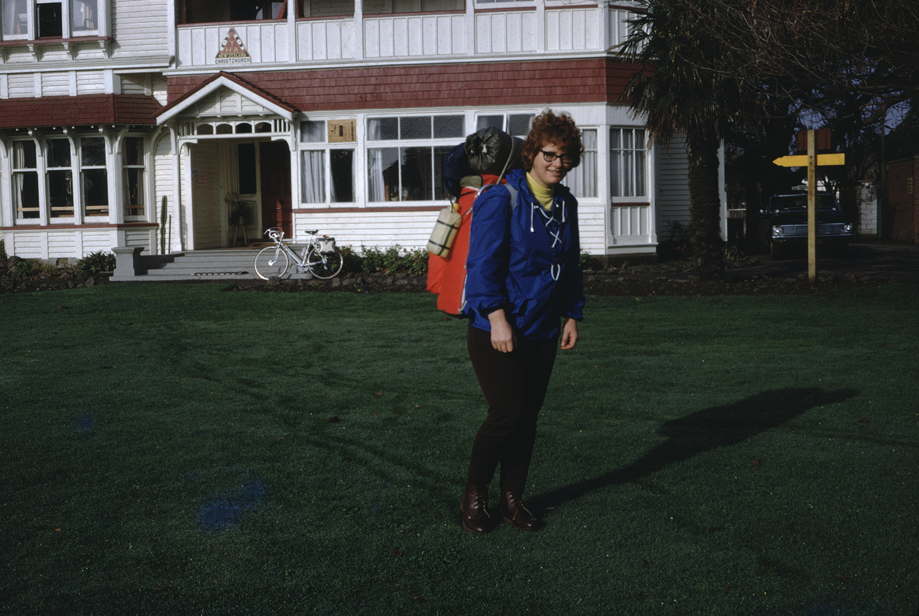 a female backpacker poses in front of a house
