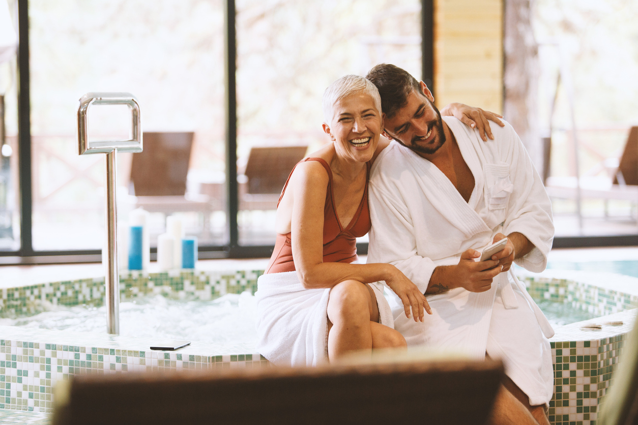 A mature woman and younger man hug while spending time at a spa