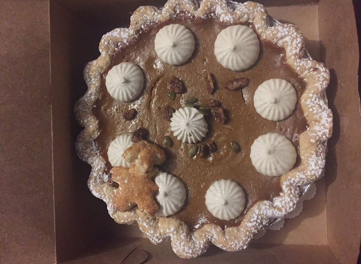 whole pumpkin pecan pie with whipped cream and pumpkin seeds