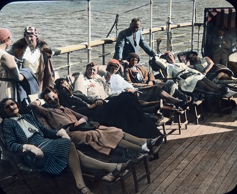 a group sit on a sundeck of a ship in the 1920s