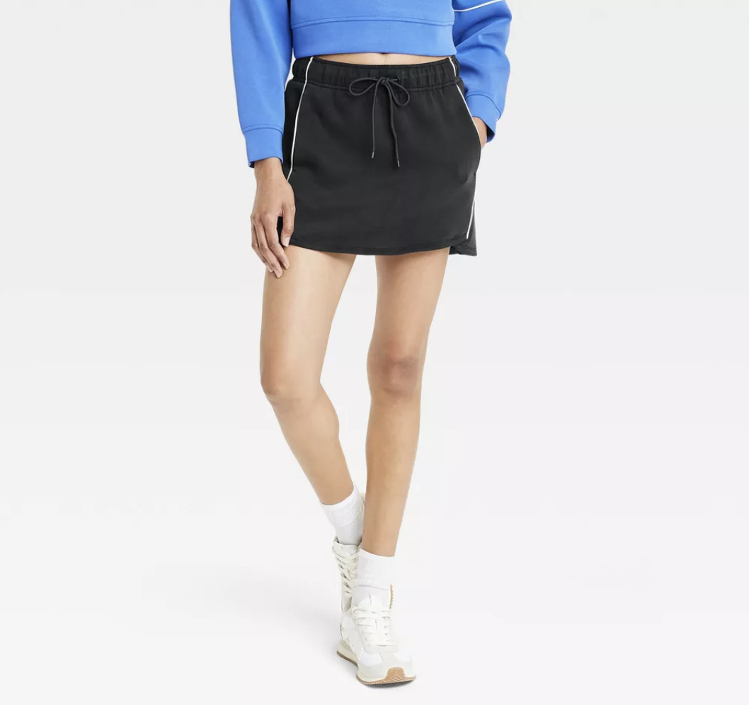 Model wearing a black athletic skirt and white sneakers from Target