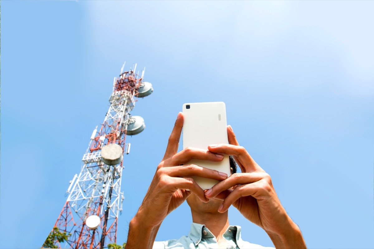 man on cell phone with telecommunication tower in the background