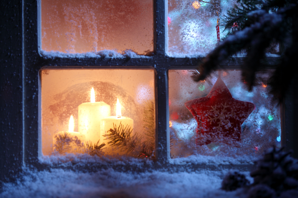 winter window has snow on sill with candles inside