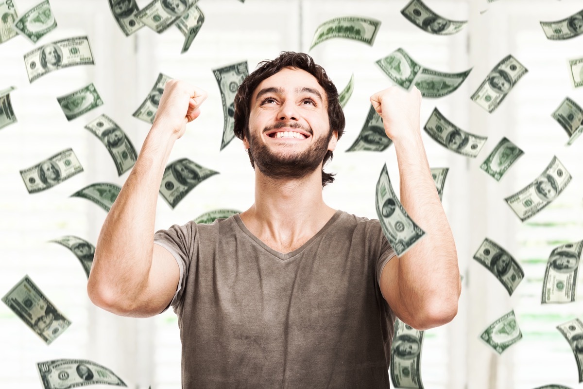 Portrait of a young man throwing money into the air against a white background