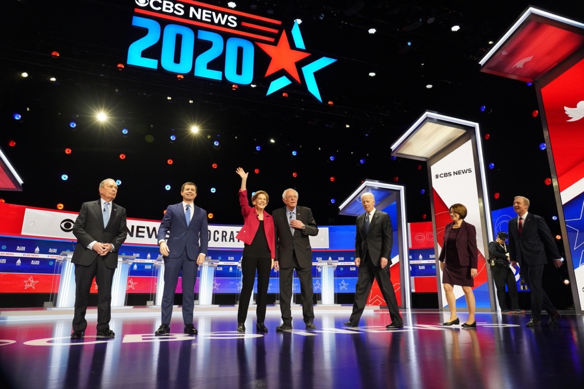 seven Democratic Candidates for U.S. President walking on stage for the debate in February 2020