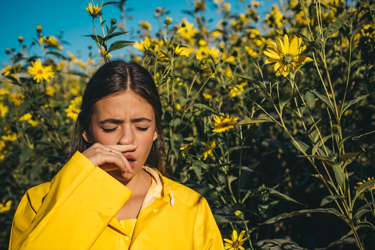 Girl sneezing near flowers
