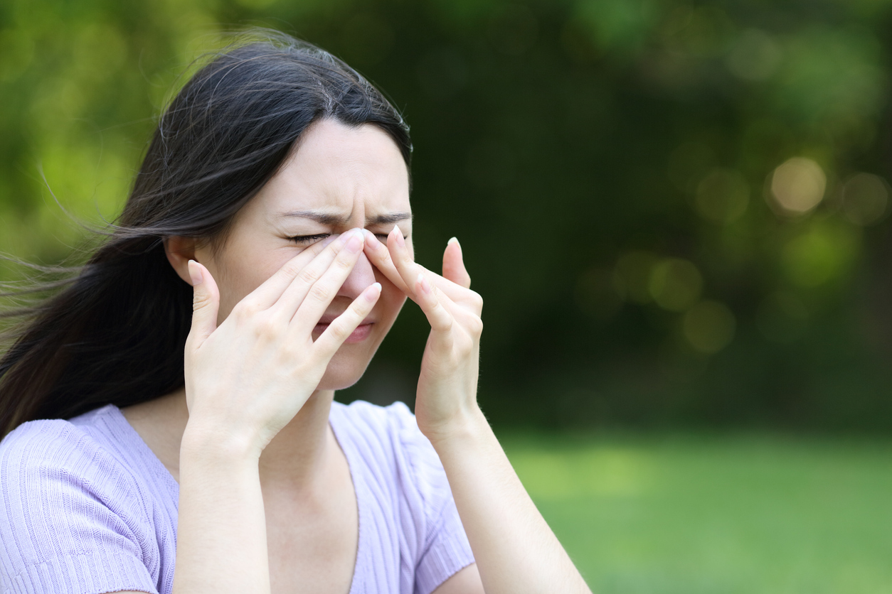 Woman with sinus headache and allergies rubbing at itchy eyes.