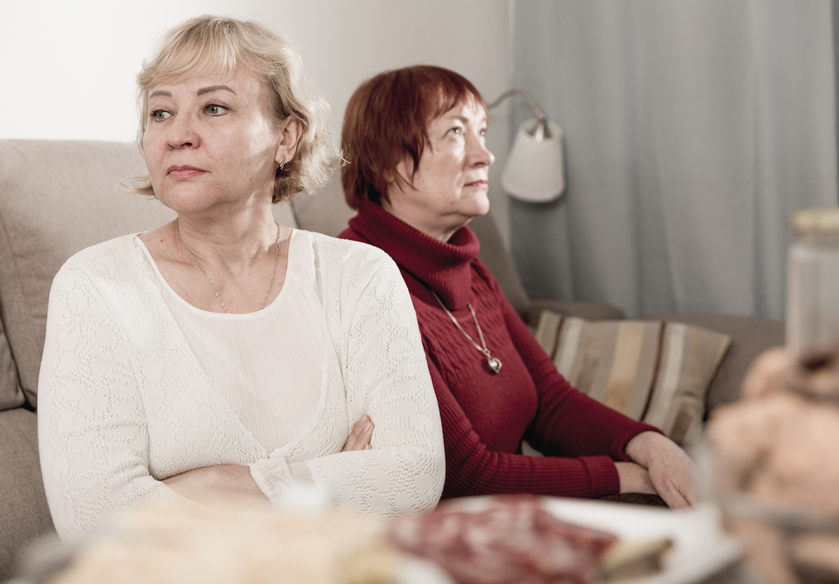 Frustrated elderly woman sitting separately having problems in relationship with female friend