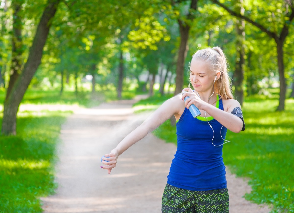 Woman spraying insect repellents on skin before run