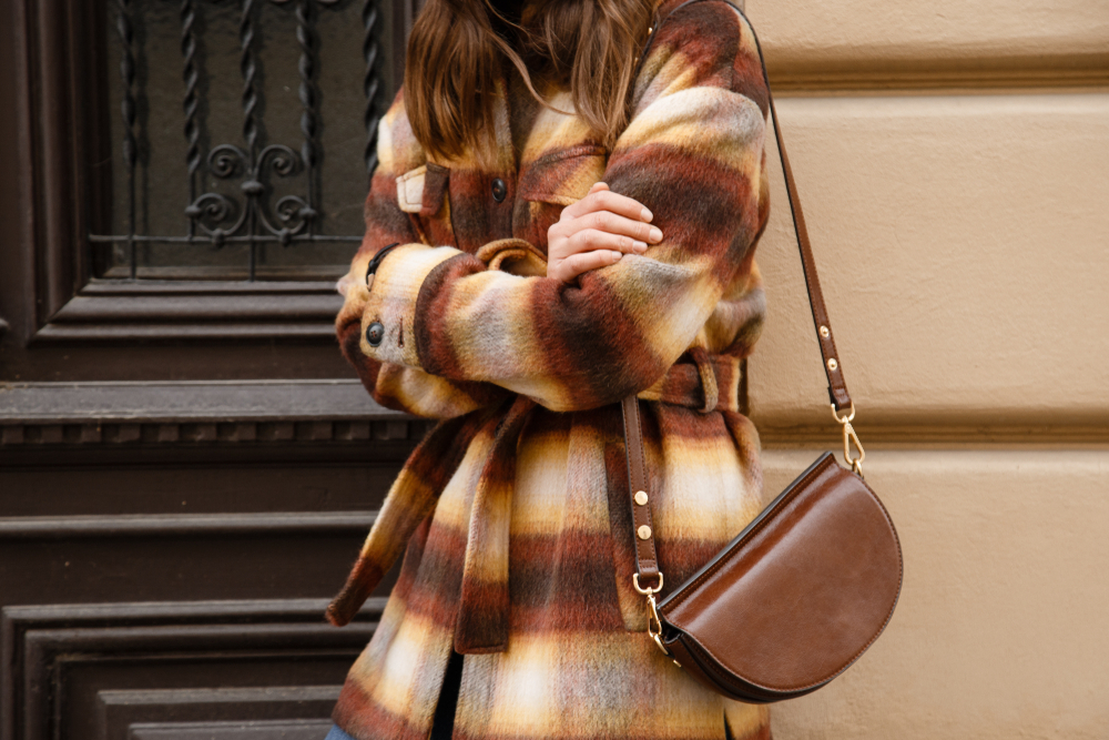 Street style concept with woman wearing plaid flannel wool jacket and brown purse