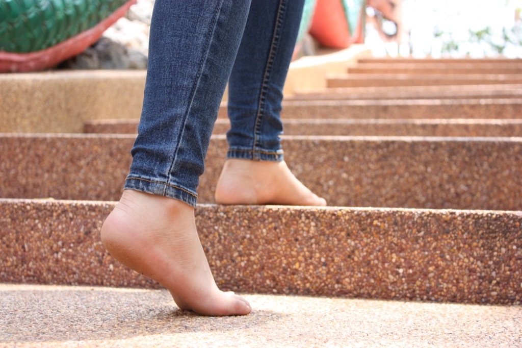 Woman walking barefoot up stairs