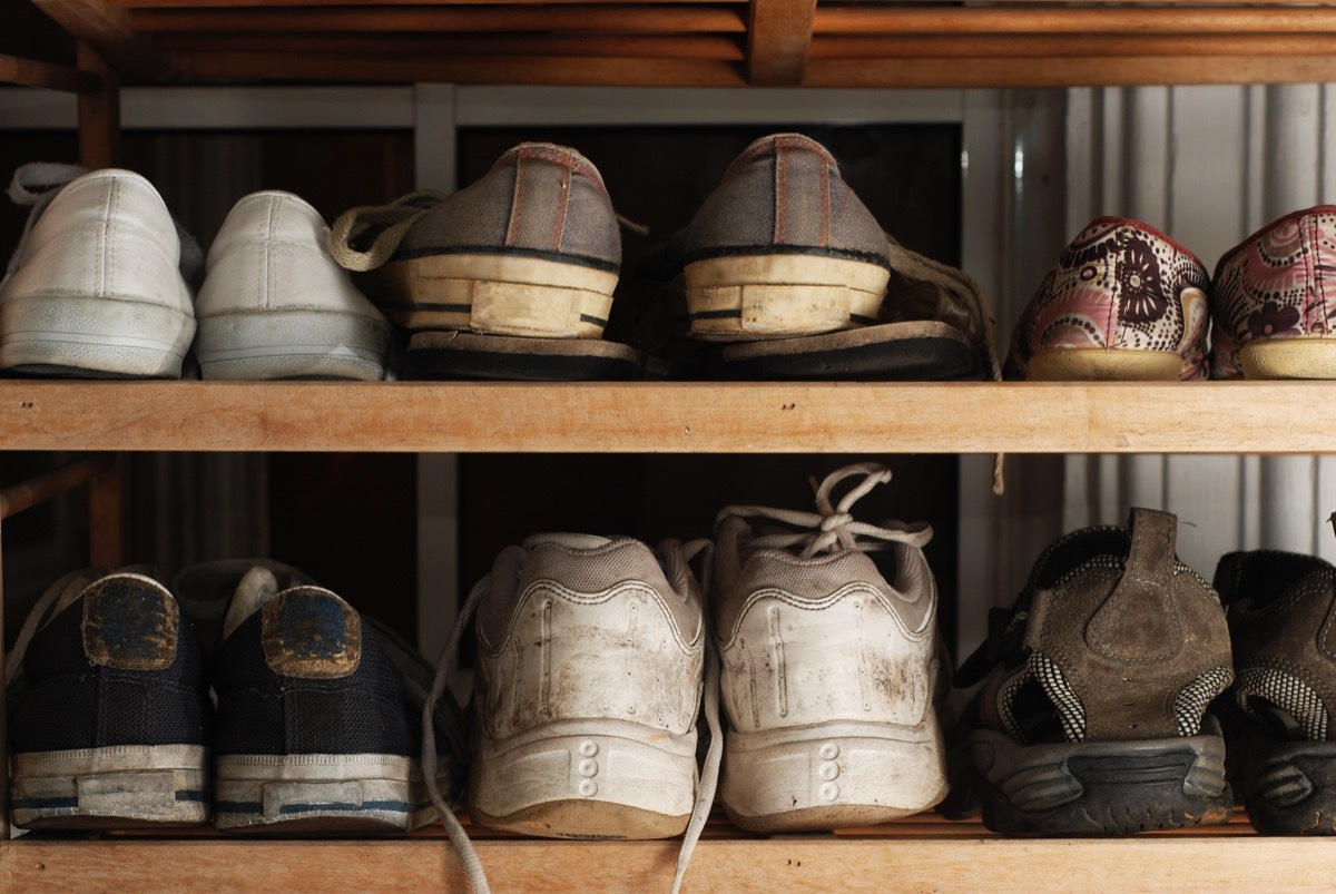 Several old and worn shoes on shoe rack