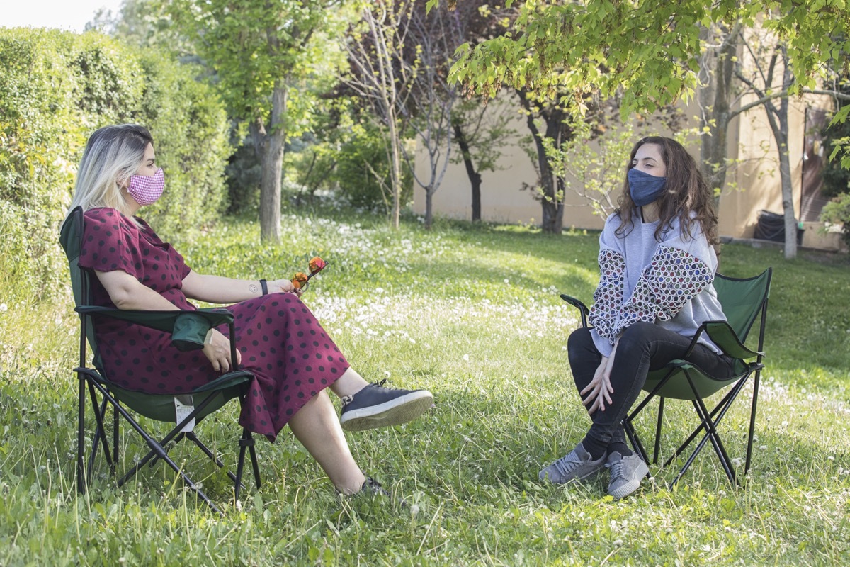 two women sitting outdoors with home made face masks.