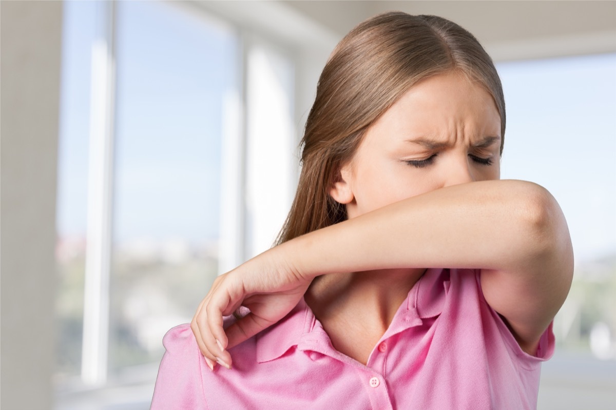 Woman sneezing or coughing into her elbow