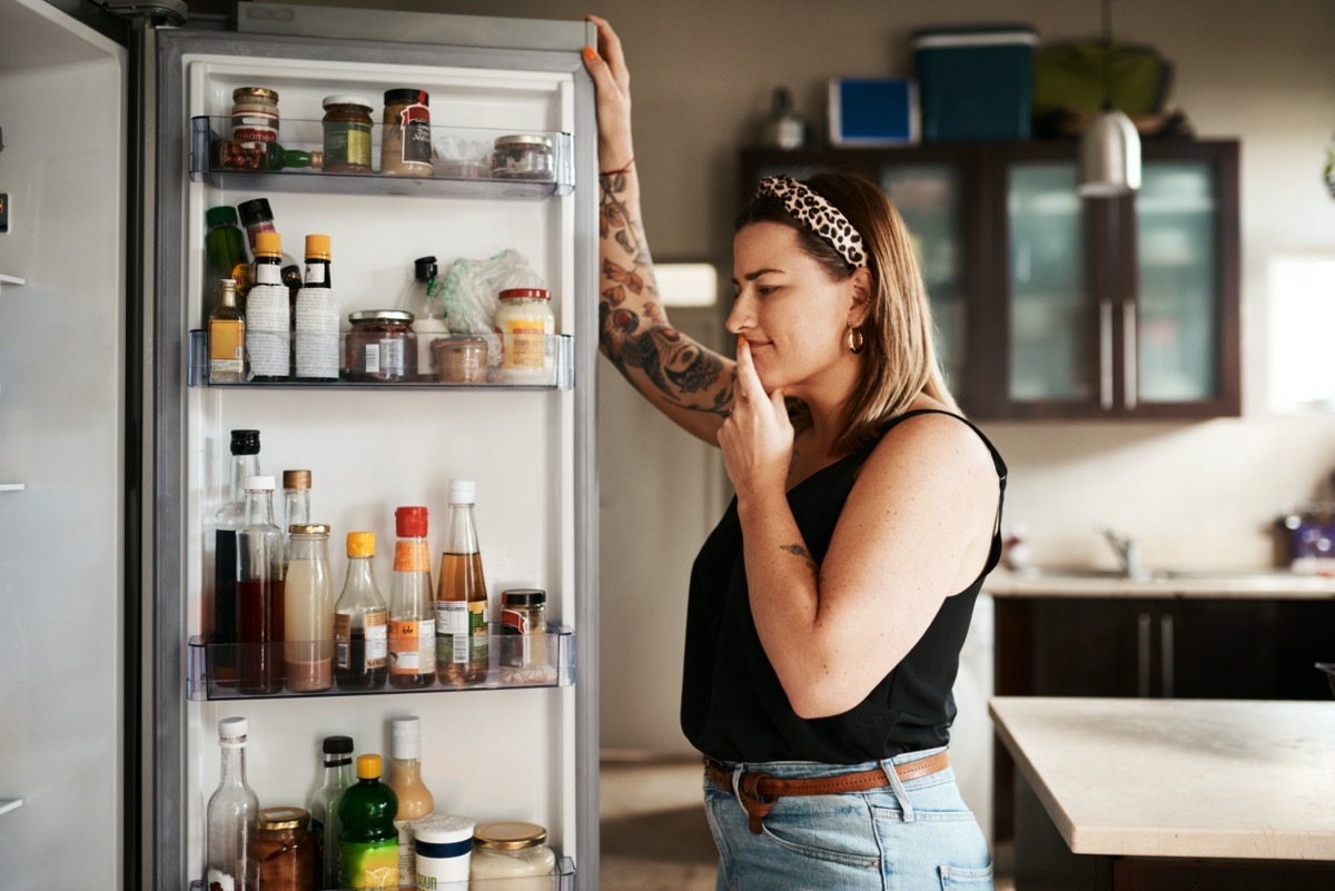 Woman standing in front of fridge deciding what to eat