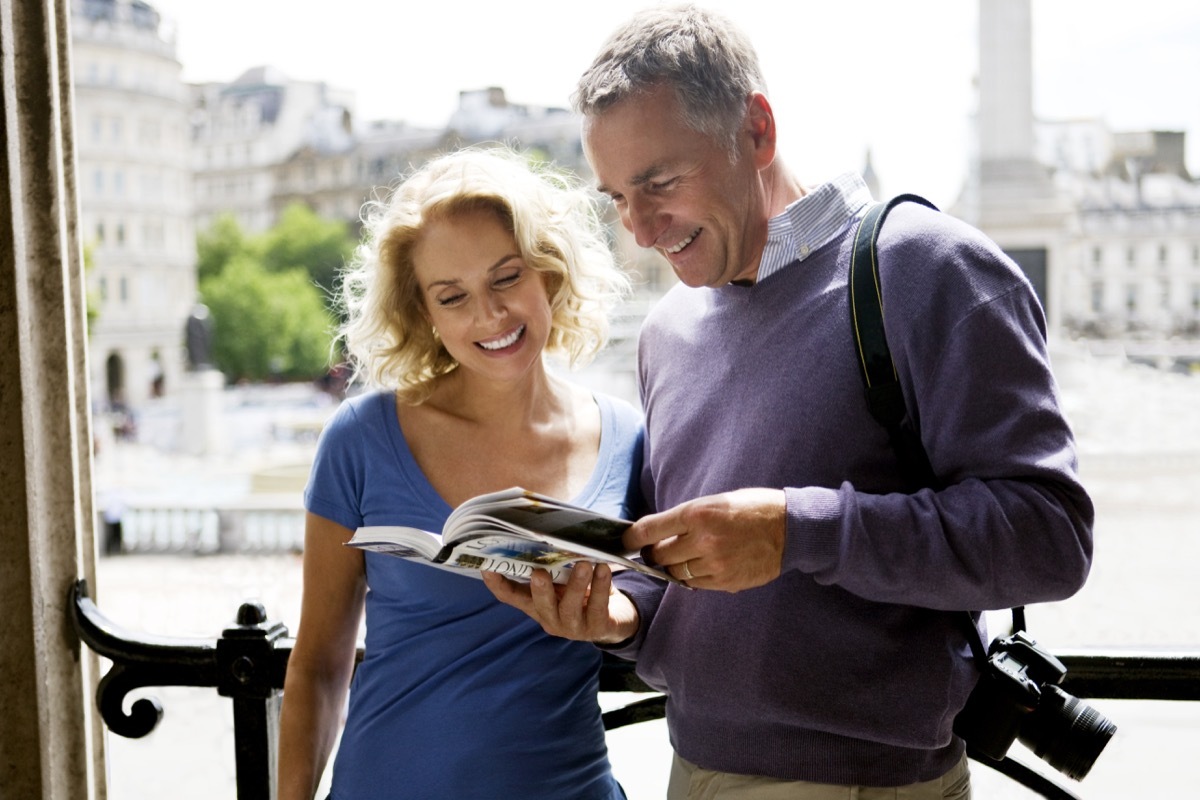 Tourist couple reading book on London sights before sightseeing