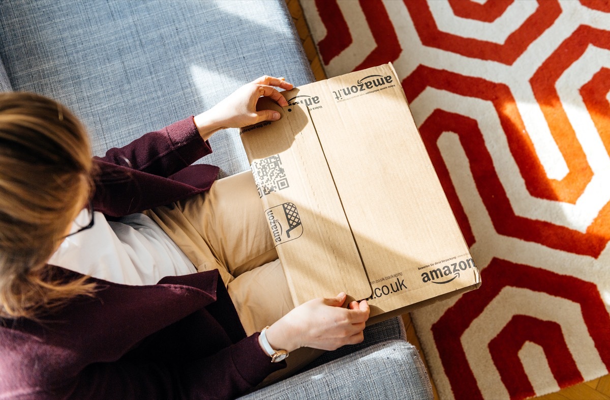 Woman unpacking unboxing Amazon cardboard box logotype printed cardboard box side.