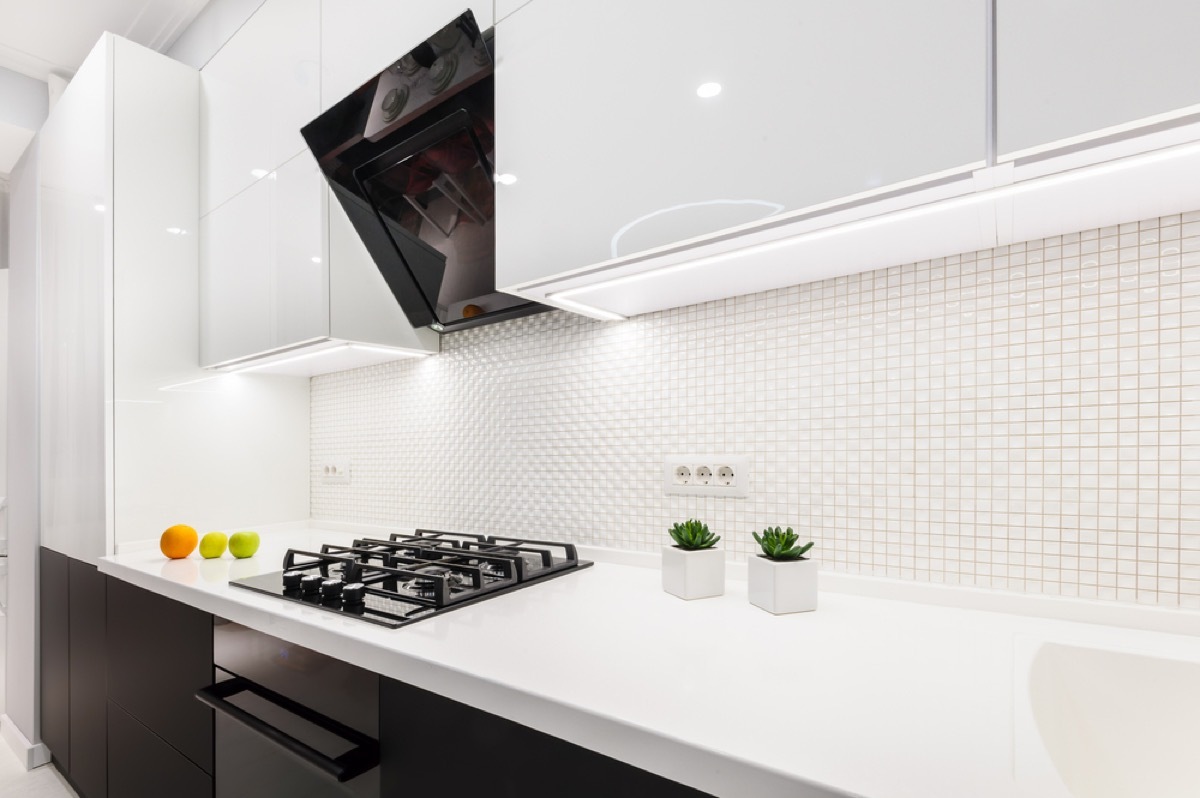 glossy white kitchen with black microwave