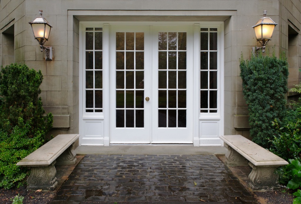 a stone walkway leading to french doors and brass sconces