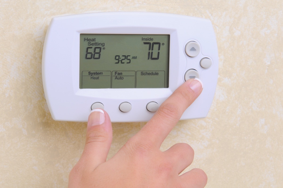 white hand setting thermostat