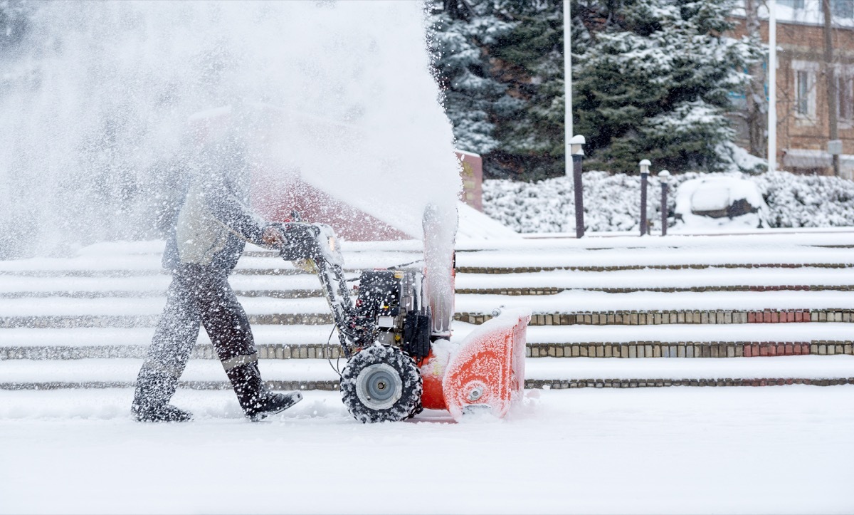 man using a snowblower in the yard